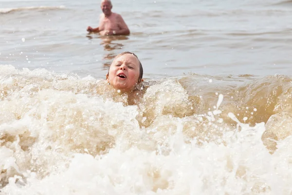 Genç çocuk ve okyanusta yüzmeye büyükbaba. Dalgalar zevk. — Stok fotoğraf