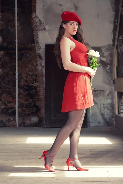 Sensual sexy bride wearing red dress and hat standing in old hou — Stock Photo, Image