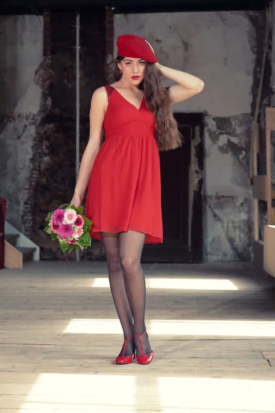 Sensual sexy bride wearing red dress and hat standing in old hou — Stock Photo, Image