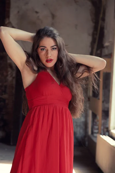 Sensual fashion woman wearing red dress posing in old urban buil — Stock Photo, Image