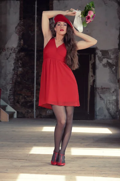 Sensual sexy bride wearing red dress and hat standing in old hou — Stock Photo, Image