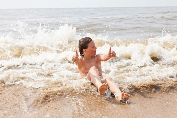 Kid boy having fun at the beach in the waves of the ocean. Stock Photo