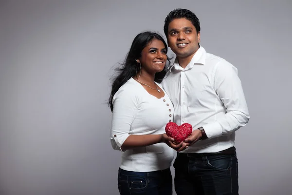 浪漫印度夫妇握着红色的心。身穿白衬衫 — 图库照片