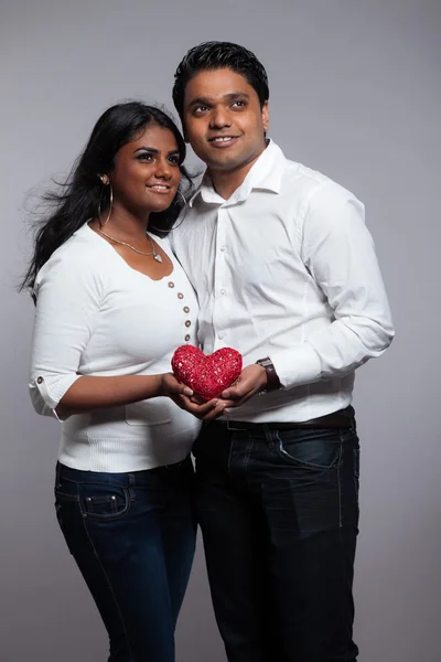 Pareja romántica india sosteniendo el corazón rojo. Usando camisa blanca y — Foto de Stock
