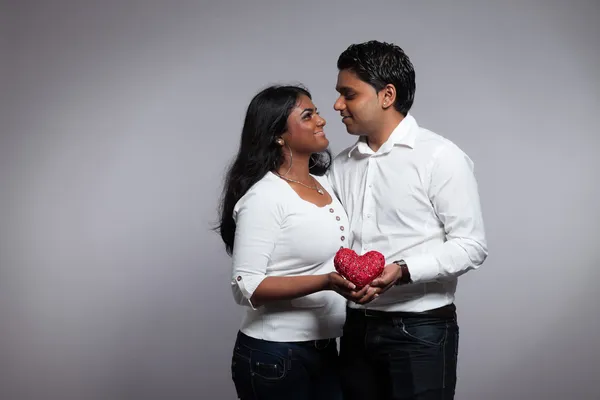 浪漫印度夫妇握着红色的心。身穿白衬衫 — 图库照片