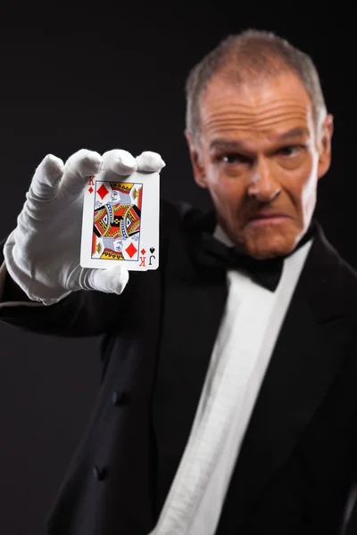 Magician holding cards. Wearing black suit. Studio shot against — Stock Photo, Image