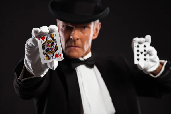 Magician with black suit and hat holding set of cards. Studio sh — Stock Photo, Image