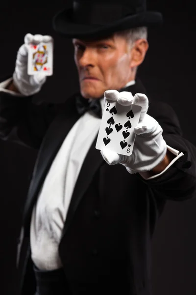 Magician with black suit and hat holding set of cards. Studio sh — Stock Photo, Image