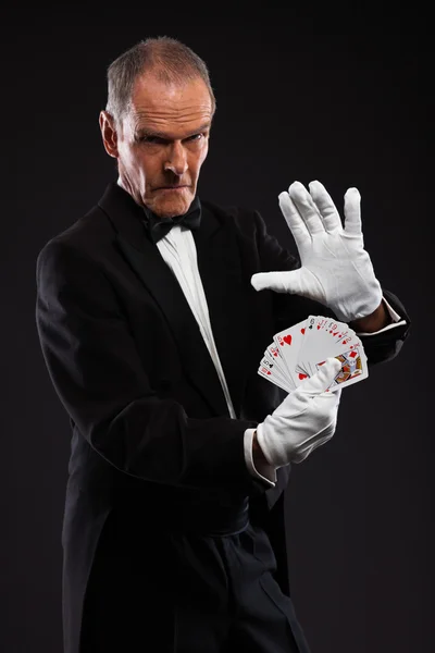 Un mago che tiene le carte. Indossa un completo nero. Studio tiro contro — Foto Stock