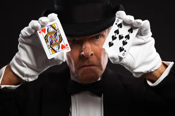 Magician with black suit and hat holding set of cards. Studio sh — Stock Photo, Image