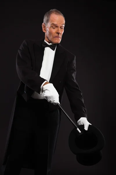 Kouzelník s černý oblek a klobouk drží kouzelná hůl. Studio s — Stock fotografie