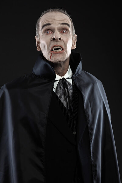 Dracula with black cape showing his scary teeth. Vamp fangs. Stu