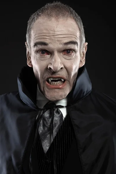 Dracula con il mantello nero che mostra i suoi denti spaventosi. Zanne di vampiro. Stu — Foto Stock