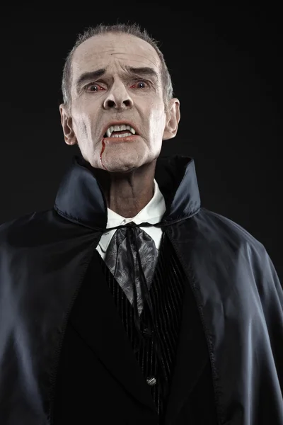 Dracula con il mantello nero che mostra i suoi denti spaventosi. Zanne di vampiro. Stu — Foto Stock