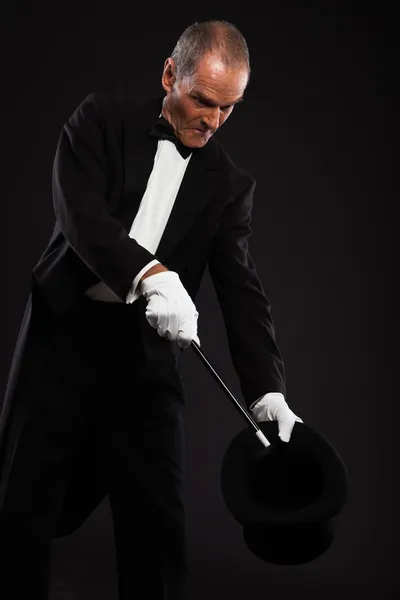 Magician with black suit and hat holding a magic stick. Studio s — Stock Photo, Image