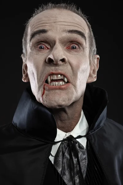 Dracula con il mantello nero che mostra i suoi denti spaventosi. Zanne di vampiro. Stu — Foto Stock