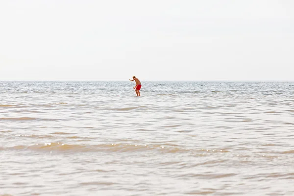 Ένας άνθρωπος πλω κουπί κωπηλασία έξω στον ωκεανό. SUP. θολό s — Φωτογραφία Αρχείου