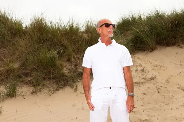 Hombre jubilado con barba y gafas de sol en paisaje de dunas de hierba wi —  Fotos de Stock