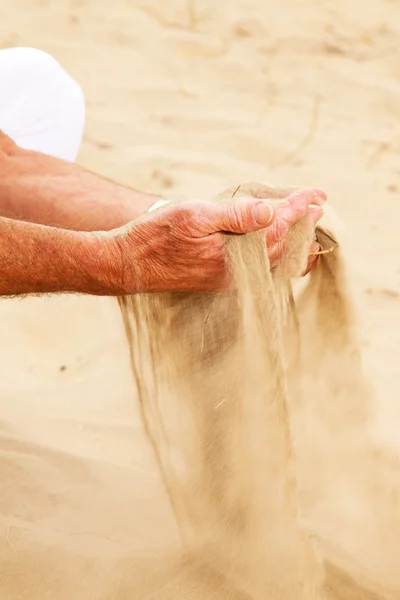 Közelkép a homok alá, idősebb férfi kezét. — Stock Fotó