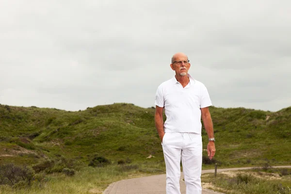 Voormalig senior man met baard en glazen buiten lopen in gr — Stockfoto