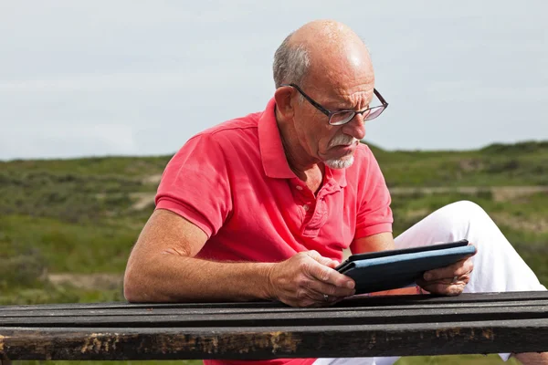 Rentner ruht sich aus und bedient sein Tablet am Tisch im Park — Stockfoto