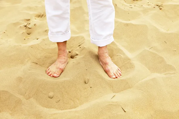 Láb magas rangú ember állt homok. fehér nadrágot visel. — Stock Fotó