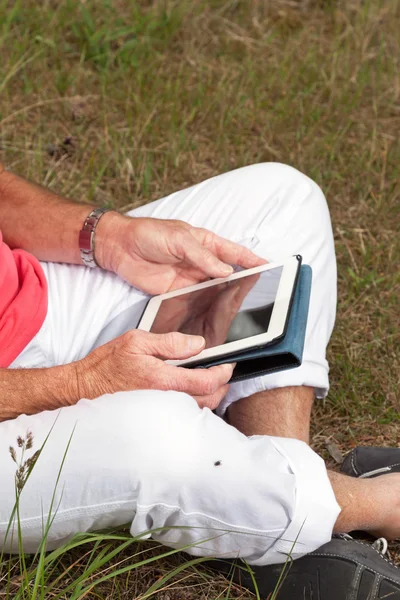 Tablet outd ile oturan üst düzey emekli adam elinde bir close-up — Stok fotoğraf