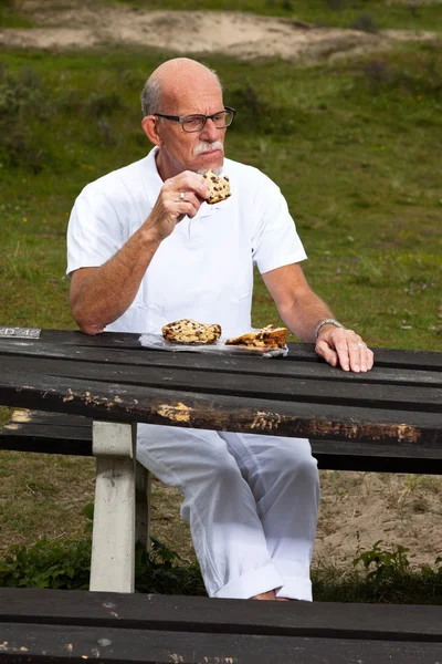 Homem aposentado com barba e óculos descansando e almoçando em g — Fotografia de Stock