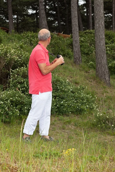 Hombre mayor usando prismáticos al aire libre. Observando las tierras altas escocesas — Foto de Stock