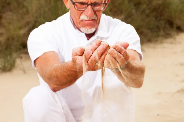 Homme âgé à la retraite avec du sable tombant de ses mains . — Photo