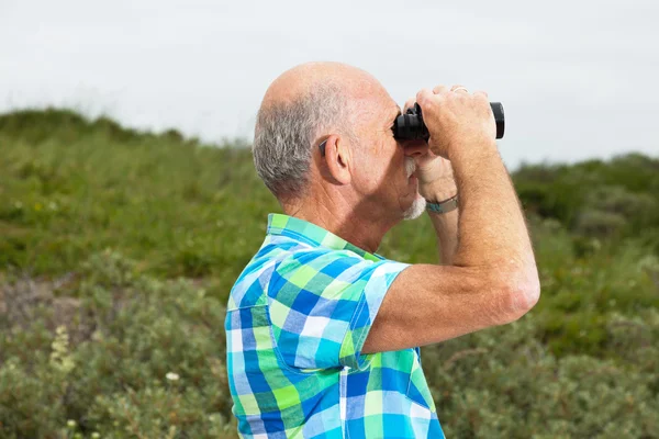 Hombre mayor con barba y gafas usando prismáticos al aire libre en g —  Fotos de Stock