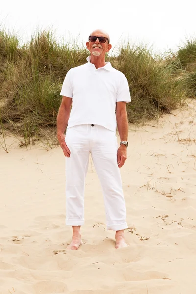 Gepensioneerde man met baard en zonnebril in gras Duin landschap wi — Stockfoto