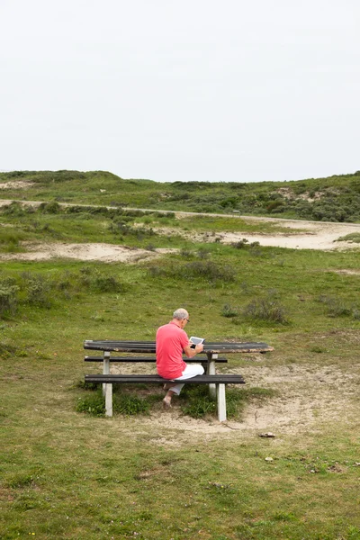 Důchodci starší muž odpočívající a použití jeho tablet v parku u stolu — Stock fotografie