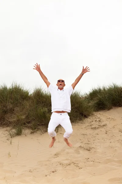 Saltando feliz jubilado hombre con barba y gafas de sol en hierba dun —  Fotos de Stock