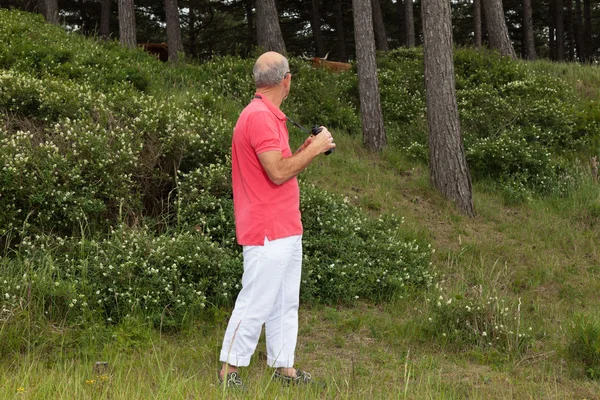 Homem idoso usando binóculos ao ar livre. Observando o planalto escocês — Fotografia de Stock