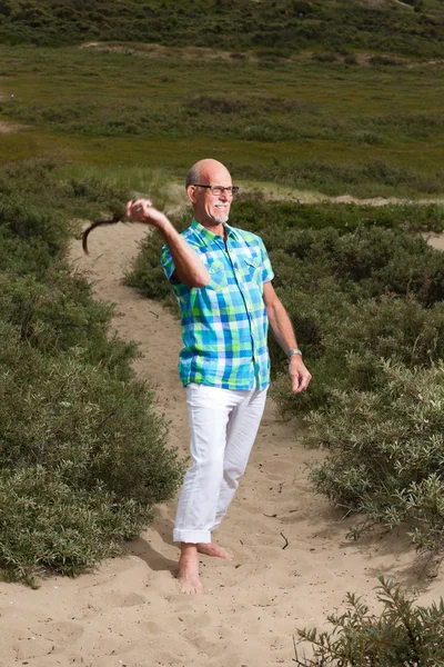 Retired senior man with beard and glasses outdoors in grass dune — Stock Photo, Image