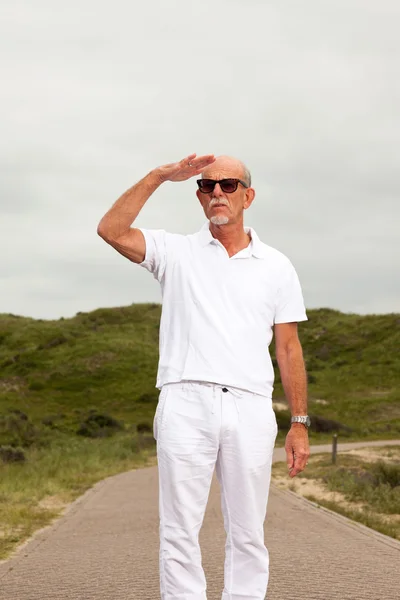 Retired senior man with beard and sunglasses walking outdoors in — Stock Photo, Image