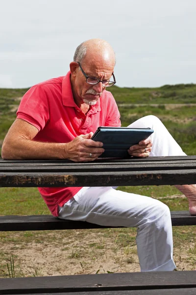 Rentner ruht sich aus und bedient sein Tablet am Tisch im Park — Stockfoto