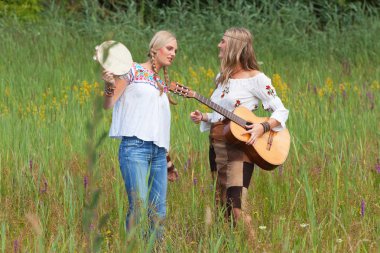 iki retro sarışın 70'lerin hippi kız akustik GUI ile müzik yapma