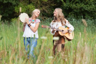 iki retro sarışın 70'lerin hippi kız akustik GUI ile müzik yapma
