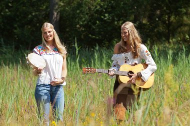 iki retro sarışın 70'lerin hippi kız akustik GUI ile müzik yapma