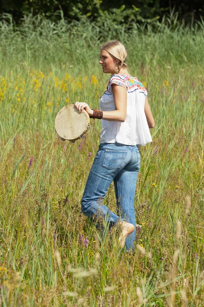 Retro blonde 70s hippie girl with tambourine outdoor in nature. — Stock Photo, Image