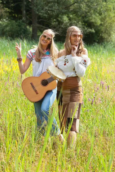 Two retro blonde 70s hippie girls with sunglasses making music w — Stock Photo, Image