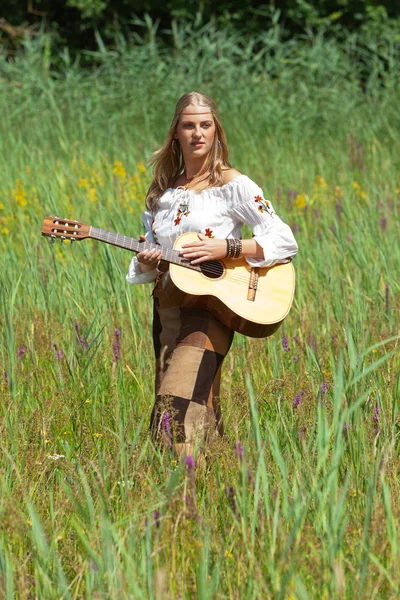 Retro blonde 70s hippie girl with acoustic guitar outdoor in nat — Stock Photo, Image