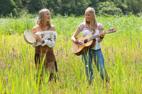 Two retro blonde 70s hippie girls making music with acoustic gui — Stock Photo, Image