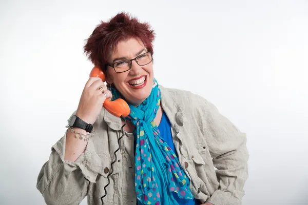 Middle aged woman calling with vintage orange telephone. Red sho — Stock Photo, Image