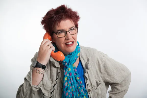 Mulher de meia-idade ligando com telefone laranja vintage. Sho vermelho — Fotografia de Stock