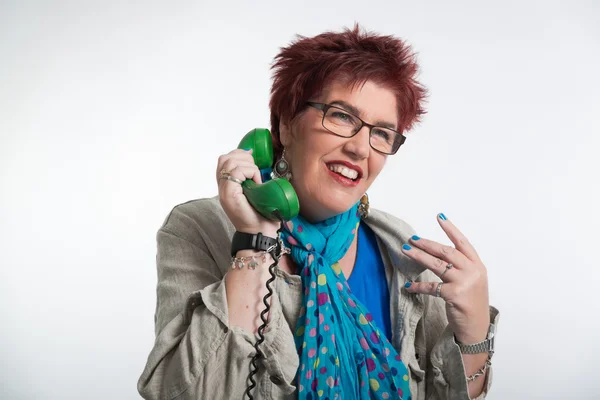 Frau mittleren Alters telefoniert mit einem grünen Telefon. red shor — Stockfoto