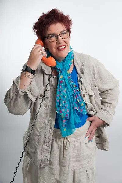 Frau mittleren Alters telefoniert mit einem orangefarbenen Telefon. roter Schuh — Stockfoto
