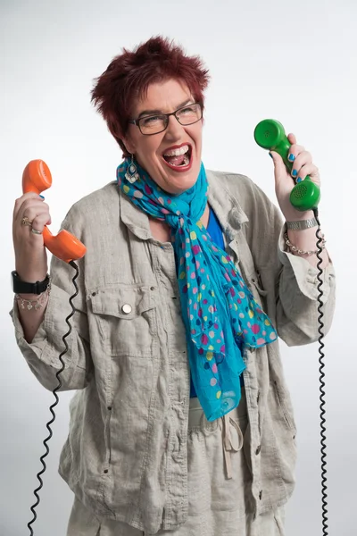 Gestresste Frau mittleren Alters schreit und hält zwei Vintage tel — Stockfoto